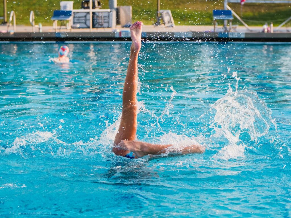 Nadadora de natación artística ejecutando una figura con la pierna en vertical en la piscina